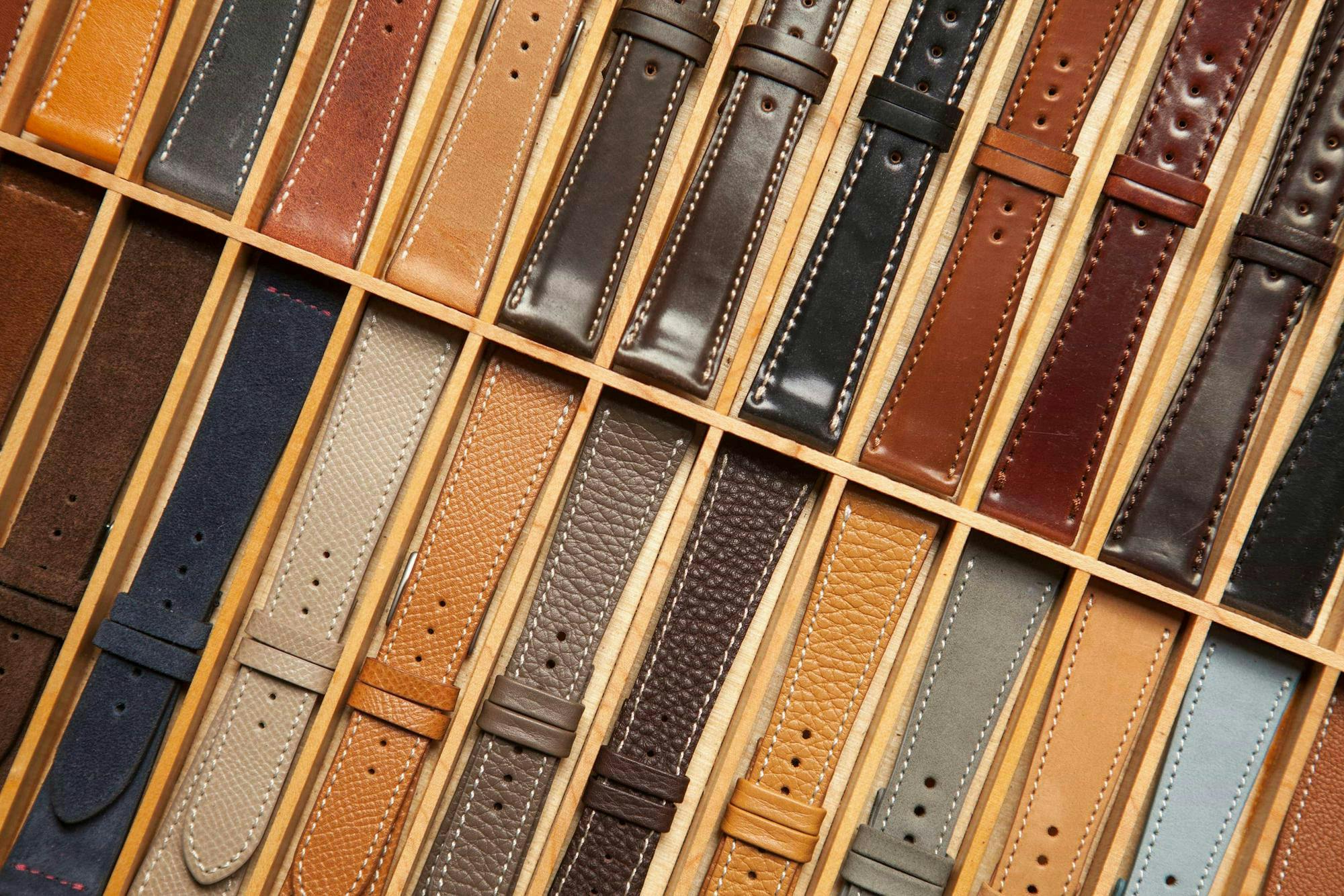 Several leather watch straps displayed in a wood case.